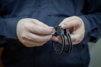 Полицейский держит в руках наручники