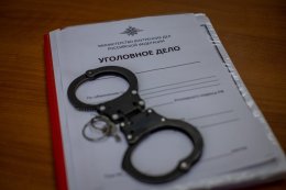 Наручники лежат на папке с уголовным делом.