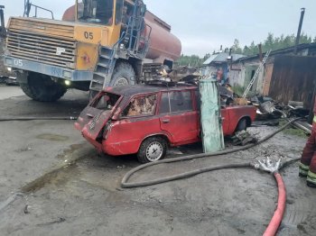 Сгоревший автомобиль возле гаража на фоне Белаза.