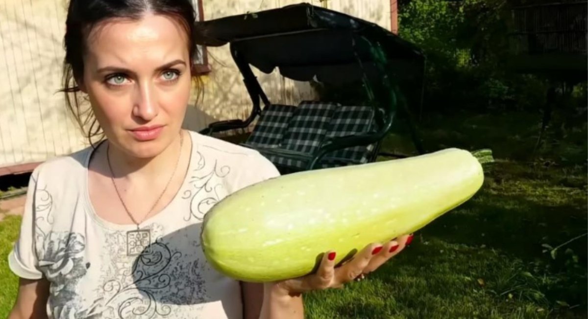 Женщина держит огромный кабачок.