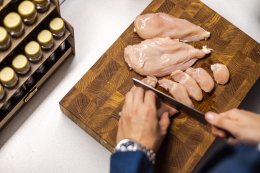 Нарезка сырого мяса курицы на доске